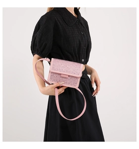 Detail of pink rhinestone crossbody bag with leather strap on a model's outfit