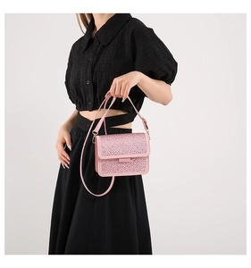 Close-up of pink rhinestone handbag with golden metal strap buckles and glossy texture