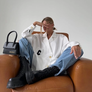 Detail der weißen Satinbluse mit Brusttasche und schwarzer Buchstaben-Stickerei C