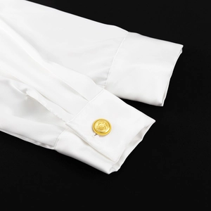 Detailaufnahme der weißen Satin-Hemdmanschette mit dekorativem goldenem Knopf und Textur