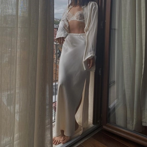 Elegant white satin maxi skirt with high side slit and lace bra in soft window lighting