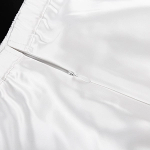 Detail of invisible zipper and pleats on white satin high-waisted maxi skirt