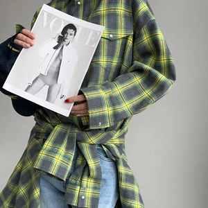 Détail d'une chemise à carreaux jaune et gris avec boutons perlés et poche à rabat