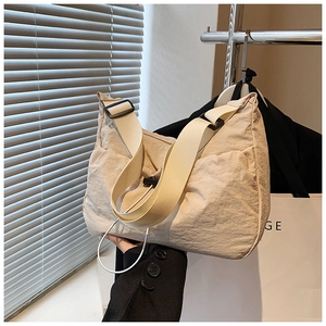 Detail of beige nylon crossbody bag featuring pleated texture and wide woven strap