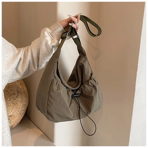 Detail of adjustable strap and drawstring buckle on this olive nylon hobo tote bag