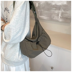 Detail of adjustable strap and drawstring closure on olive nylon crossbody bag for women