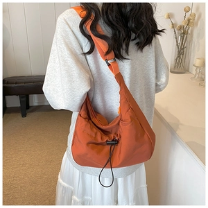 Detail view of the rust red nylon crossbody dumpling bag showing texture and wide strap