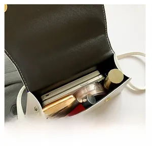 Detail view of white leather crossbody bag interior showing daily capacity and metal buckle