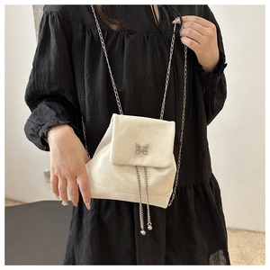 Detail of cream white mini backpack featuring metal butterfly clasp and chain straps