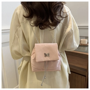 Detailed view of pink velvet backpack with silver butterfly buckle and long chain tassels