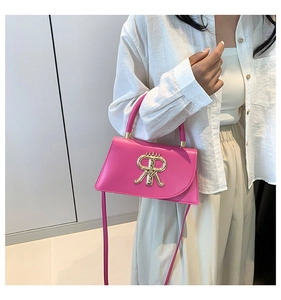 Vue détaillée du petit sac carré rose avec logo doré porté par un mannequin