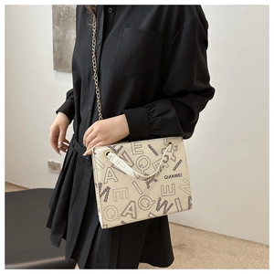 Detail of a vintage tote bag with black letter prints and a golden chain strap on a model
