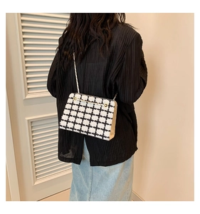 Detailed view of black and white tweed crossbody bag with a gold metal chain strap
