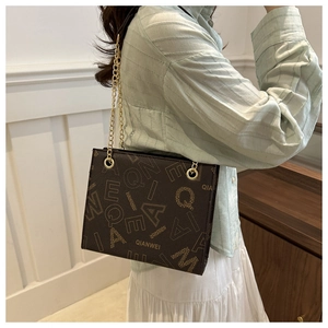 Close-up of the chain strap and QIANWEI brand logo on the brown leather tote bag