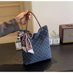 Dettaglio della borsa tote in denim blu con cuciture bianche e foulard di seta con orsetto