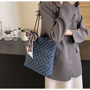 Dettaglio della borsa tote in denim con cuciture a rombi, manico in pelle e foulard
