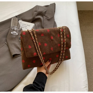 Detail of brown corduroy tote bag with strawberry print and gold chain strap