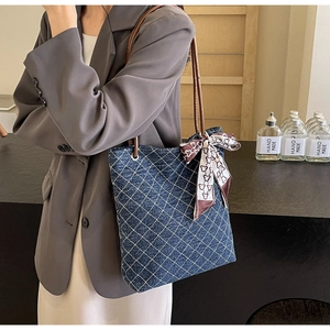 Dettaglio borsa tote in denim blu con motivo trapuntato bianco e manici in pelle