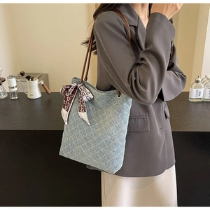 Dettaglio della borsa tote in denim trapuntato con manici in pelle e foulard di seta