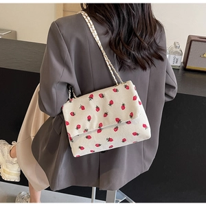 Detail of strawberry print corduroy shoulder bag with metal and leather chain strap
