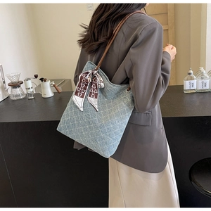 Dettaglio della borsa tote in denim blu con motivo a griglia e sciarpa di seta orso