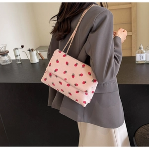 Detail of pink corduroy strawberry tote bag with gold chain strap on shoulder