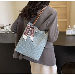 Dettaglio della borsa tote trapuntata blu in denim con manici marroni e fiocco decorativo