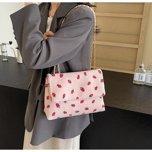 Pink corduroy tote bag with red strawberry print and golden chain strap detail