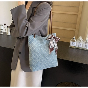 Dettaglio borsa tote trapuntata in denim blu con tracolla in pelle e foulard di seta stampato