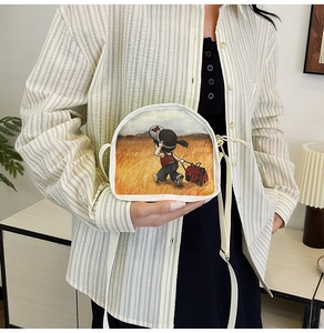 Detail of canvas crossbody bag featuring artistic illustration of person in wheat field