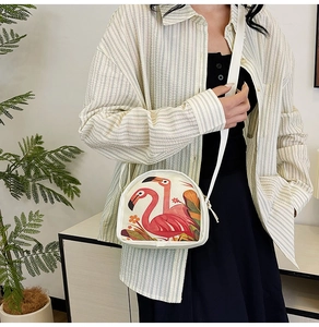 Detail of white canvas crossbody bag featuring pink flamingo and tropical leaf print