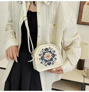 Detail of embroidered floral canvas bag showing the semicircular shape and adjustable strap