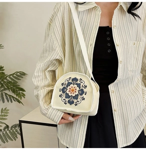 Detail of floral embroidery on a beige canvas crossbody bag with elegant ethnic patterns
