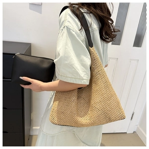Close-up of woven straw hobo bag with black leather strap and matching pouch