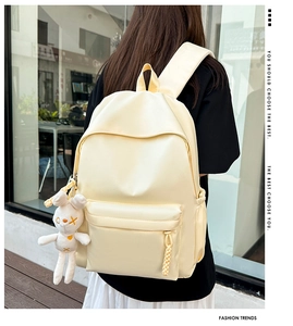Creamy yellow minimalist waterproof backpack with a plush bunny charm on city background