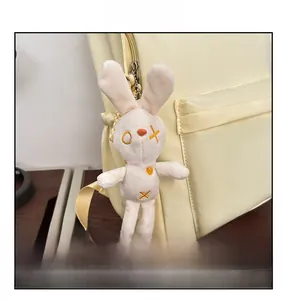Close-up of a white plush rabbit charm with heart embroidery on a yellow backpack