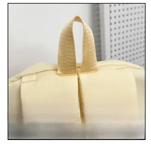 Detail of reinforced padded handle and wide shoulder straps on cream canvas backpack