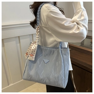 Macro detail of a light blue tote bag featuring crinkled texture and woven rope handle