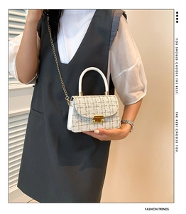 Détail d'un sac bandoulière en tweed avec chaîne dorée et poignée ronde porté par un mannequin