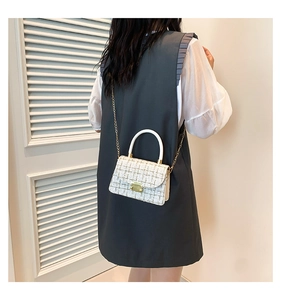 Détail d'un sac bandoulière en tweed avec tissage métallisé, chaîne dorée et anse