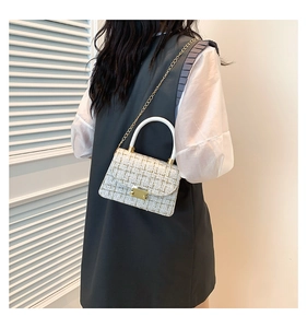 Détail du sac bandoulière en tweed blanc avec chaîne dorée porté par un mannequin