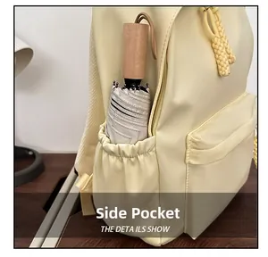Detail view of the side elastic pocket on a pale yellow backpack holding a wooden umbrella