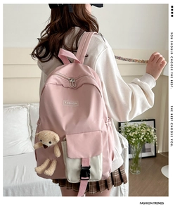 Pink fashion backpack detail featuring a plush bear charm and white contrast front pocket
