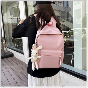Close-up of pink school backpack with cute white rabbit plush keychain accessory