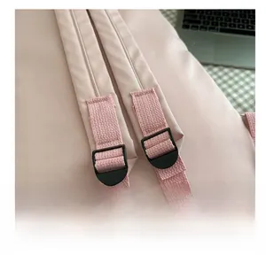 Close-up of adjustable shoulder strap buckle on a pink minimalist backpack