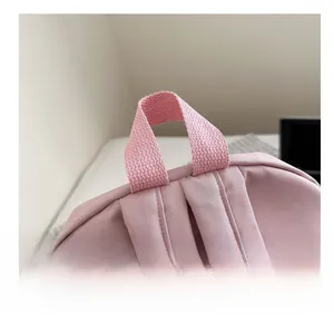 Detail of soft pink backpack showing reinforced top handle and wide padded shoulder straps