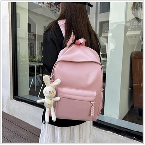 Detail of pink minimalist school backpack with a cute white bunny plush pendant