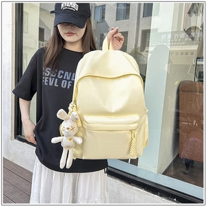 Close-up of light yellow waterproof nylon backpack with a cute white bunny plush charm