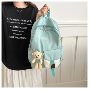 Detail of mint green lightweight school backpack with bear charm on a female model