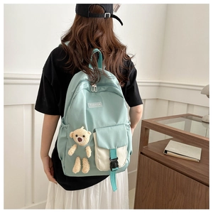 Detail of mint green backpack with plush bear pendant and functional buckle strap